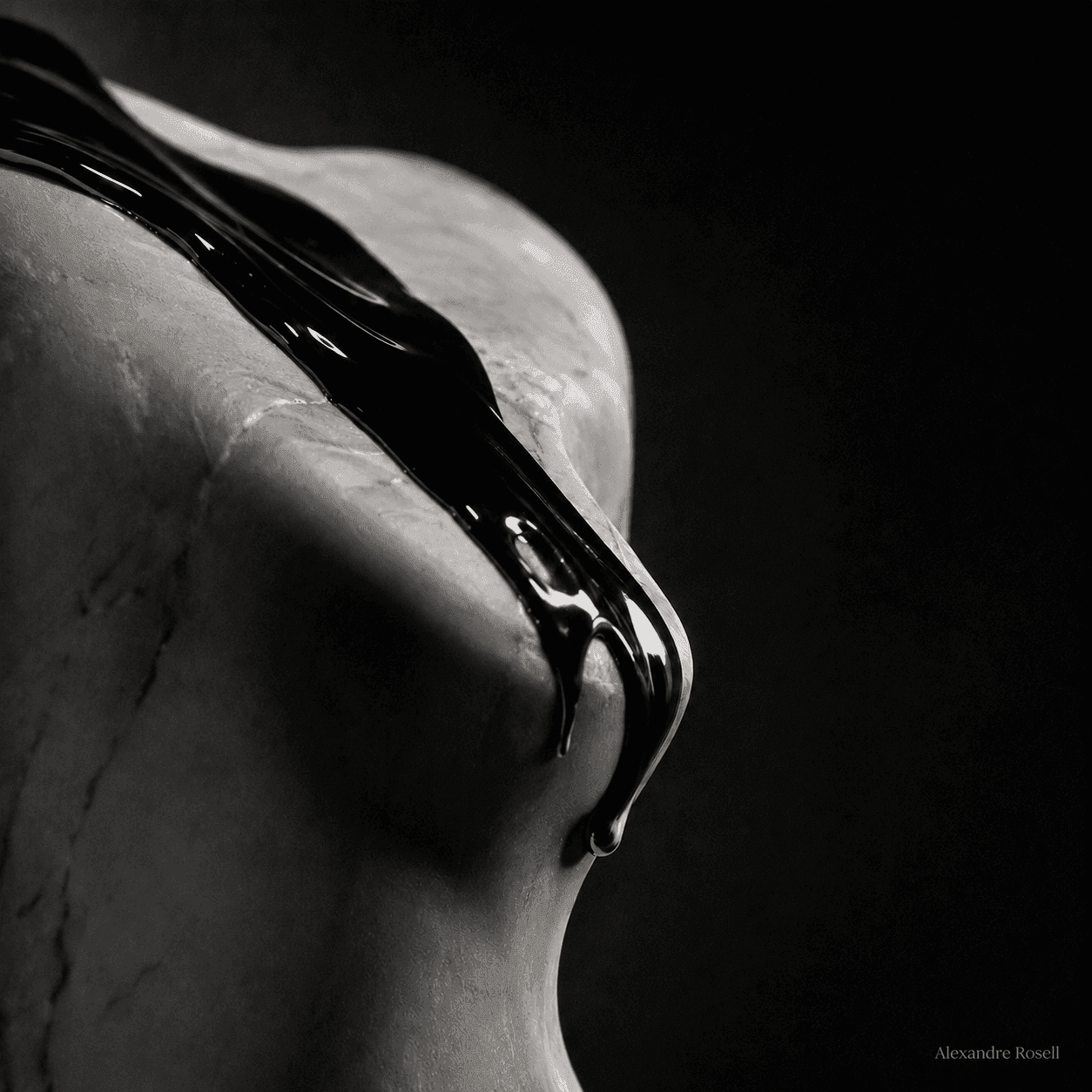 A pale marble torso sheathed in liquid black, sculpted by a single shaft of light against deep shadow.