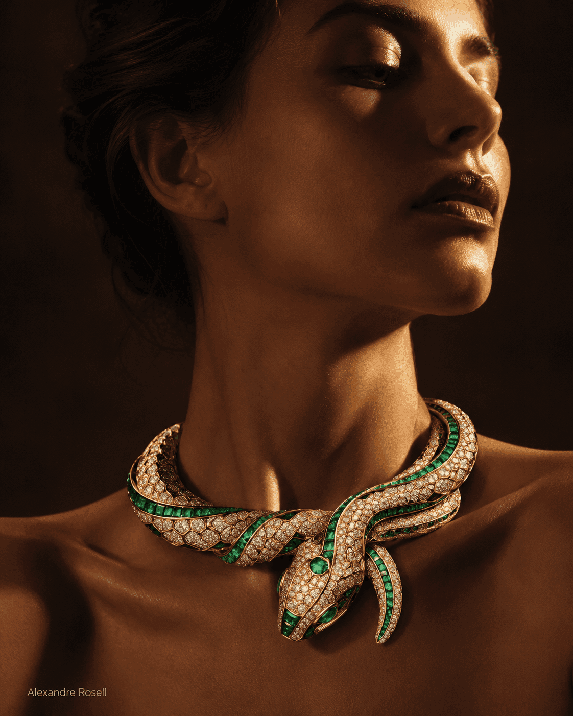 A diamond and emerald serpent necklace coiled at a woman's throat in warm light.